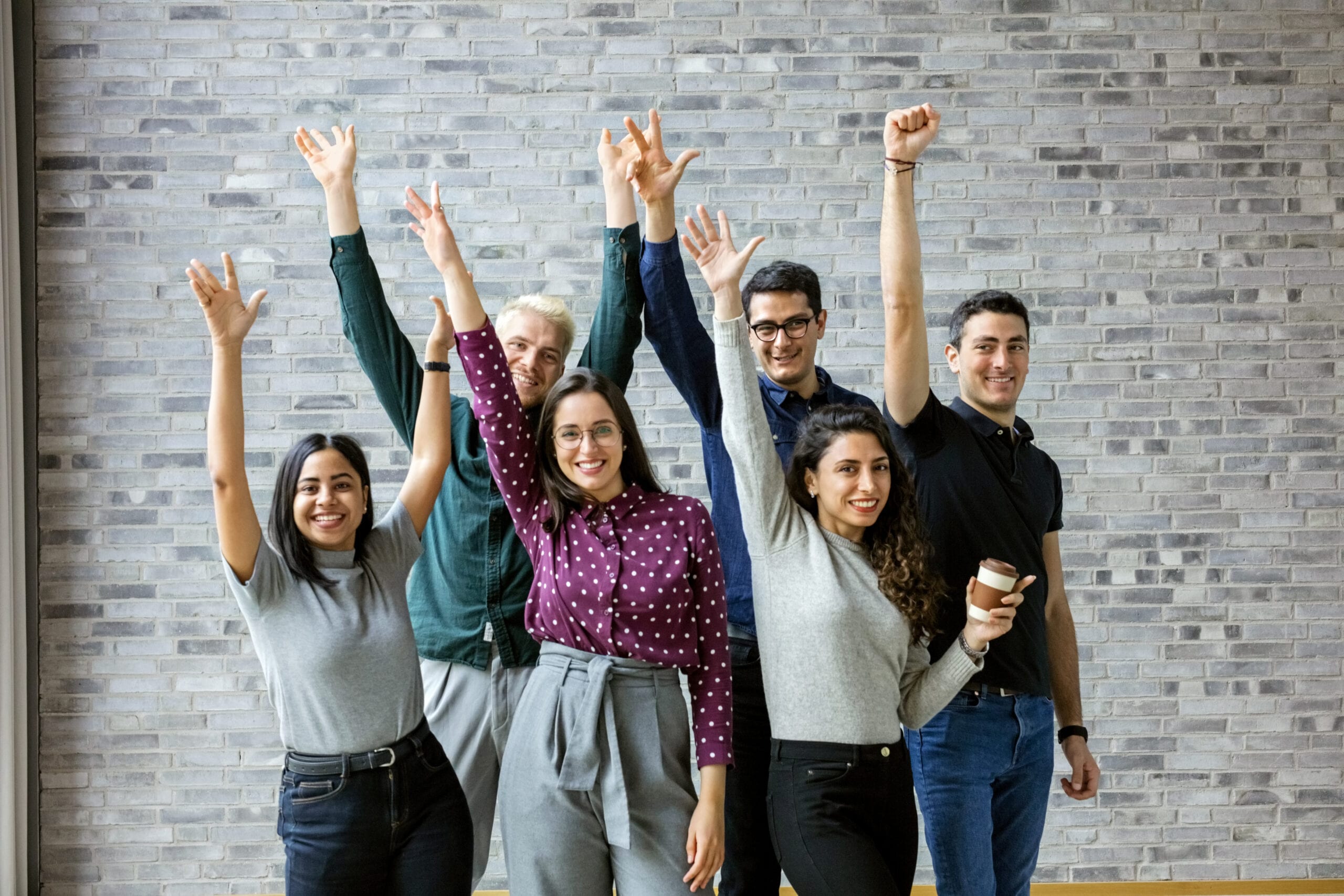 6 collaborateurs qui brandissent le poing en souriant