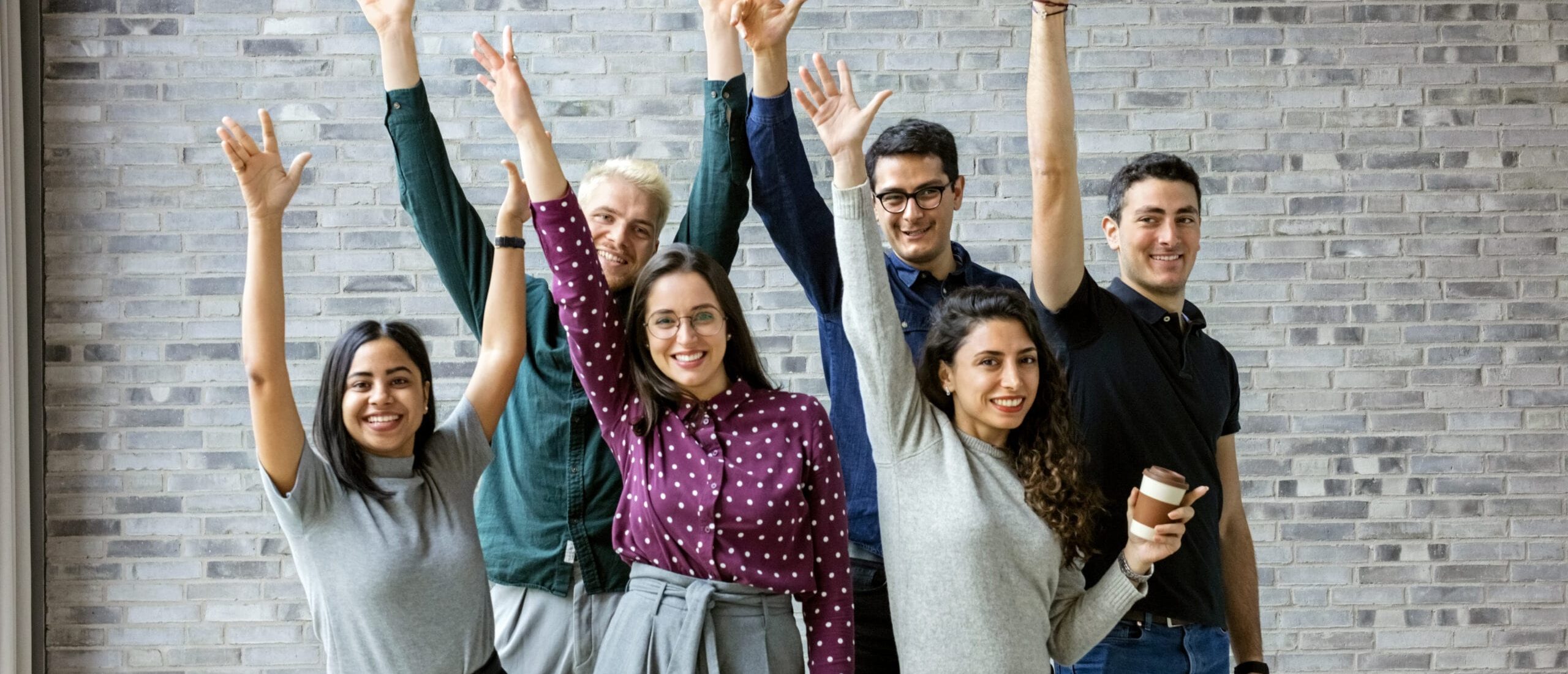 6 collaborateurs qui brandissent le poing en souriant